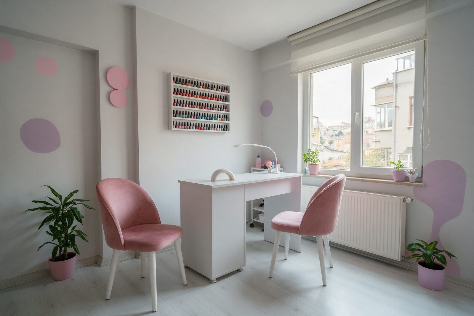 Stüdyo: beyaz manikür masası, pembe kadife sandalyeler, oje rafı ve pencere